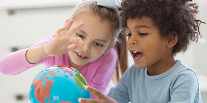A boy and a girl playing together with a world globe.